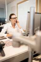 Serious businesswoman using mobile phone while sitting at desk