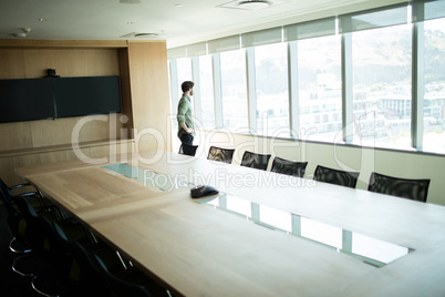 Businessman looking through window in meeting room