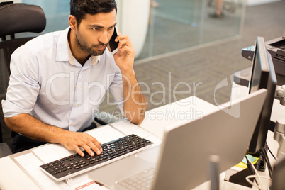Focused businessman talking on phone while working in office