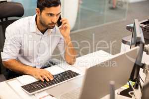 Focused businessman talking on phone while working in office