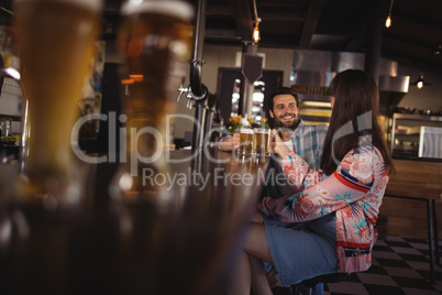 Happy couple interacting while having beer at counter