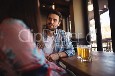 Couple interacting while having beer at counter