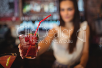 Female bartender serving a cocktail drink at bar counter