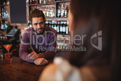 Male bar tender interacting with customer at pub
