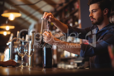 Male bar tender opening a bottle of wine