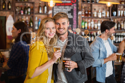 Young friends holding beer glasses in pub