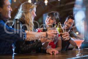 Cheerful friends toasting drinks at bar counter