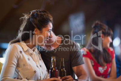 Cheerful woman looking away while holding beer bottle