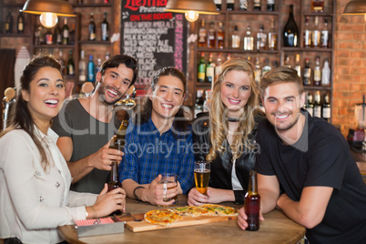 Portrait of happy friends having pizza with beer