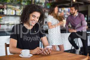 Smiling young man using mobile phone while sitting in restaurant