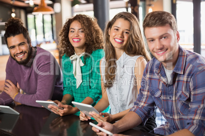 Portrait of friends holding digital tablets in restaurant
