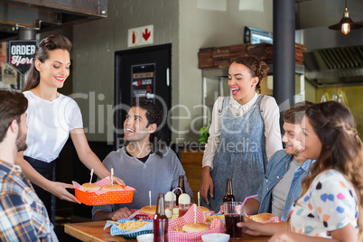 Friends looking at waitress serving food in restaurant