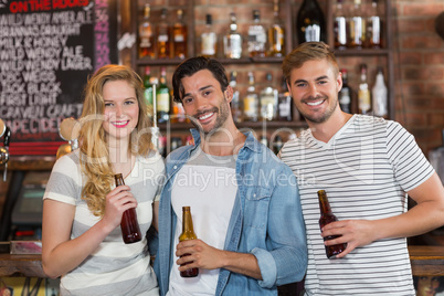 Happy friends posing with beer bottles at pub