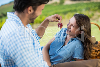 Man feeding grapes to cheerful partner