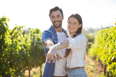 Portrait of smiling young couple holding hands at vineyard