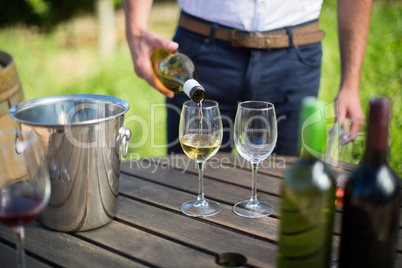 Mid section of man pouring wine in glass