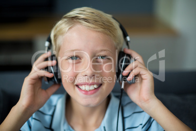 Smiling boy listening to music on headphones in living room