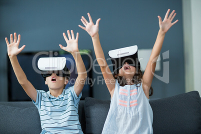 Siblings using virtual reality headset in living room