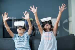 Siblings using virtual reality headset in living room