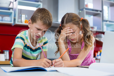 Tense siblings doing homework in kitchen