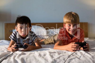 Siblings playing video game on bed