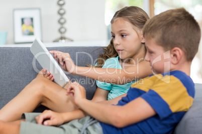 Siblings using digital tablet in living room