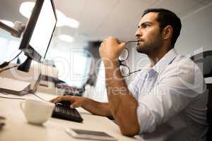 thoughtful businessman using computer at office desk