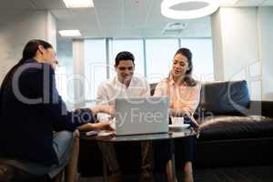 Business people discussing over laptop at office