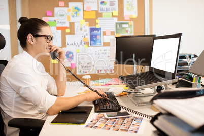 Smiling businessman talking on phone at creative office