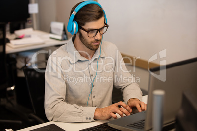 Businessman listening music through headphones while working