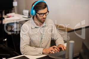 Businessman listening music through headphones while working