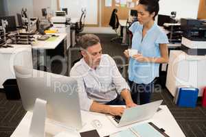 High angle view of businesswoman standing by male colleague in office