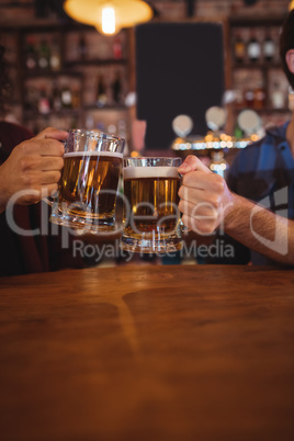 Two young men toasting their beer mugs