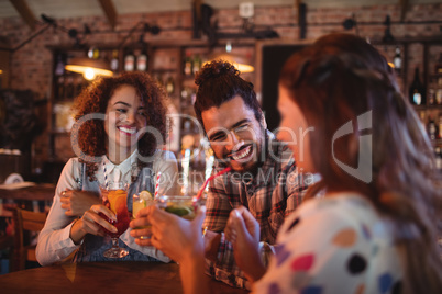 Young friends interacting with each other having drinks
