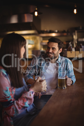 Couple interacting while having beer at counter