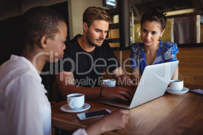 Friends using laptop while having coffee