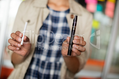 Mid-section of female executive holding electronic cigarette