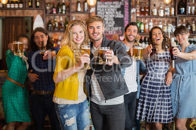Cheerful friends holding beer glasses in pub