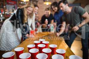 Friends enjoying beer pong game in bar