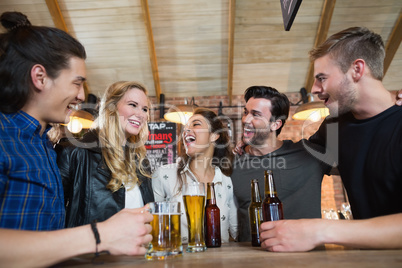 Happy friends standing by beer glass and bottles on table