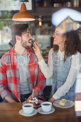 Happy woman feeding cherry to male friend