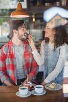 Happy woman feeding cherry to male friend