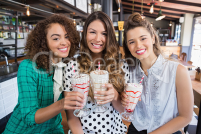 Cheerful female friends posing with drinks in restaurant