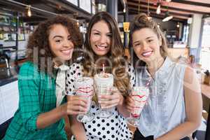 Cheerful female friends posing with drinks in restaurant