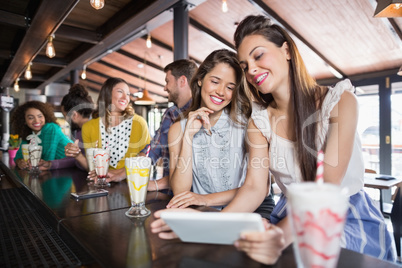 Friends using digital tablet in restaurant