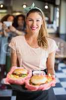 Happy waitress serving burgers in restaurant