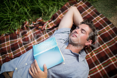Man with book sleeping on blanket