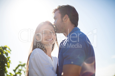 Happy woman hugging boyfriend amidst plants at vineyard