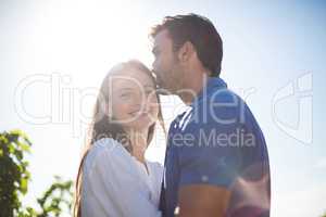 Happy woman hugging boyfriend amidst plants at vineyard