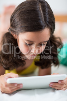 Girl using digital tablet on bed in bedroom